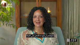 A professional woman with curly black hair smiling confidently in a well-lit indoor setting; career-focused and approachable.