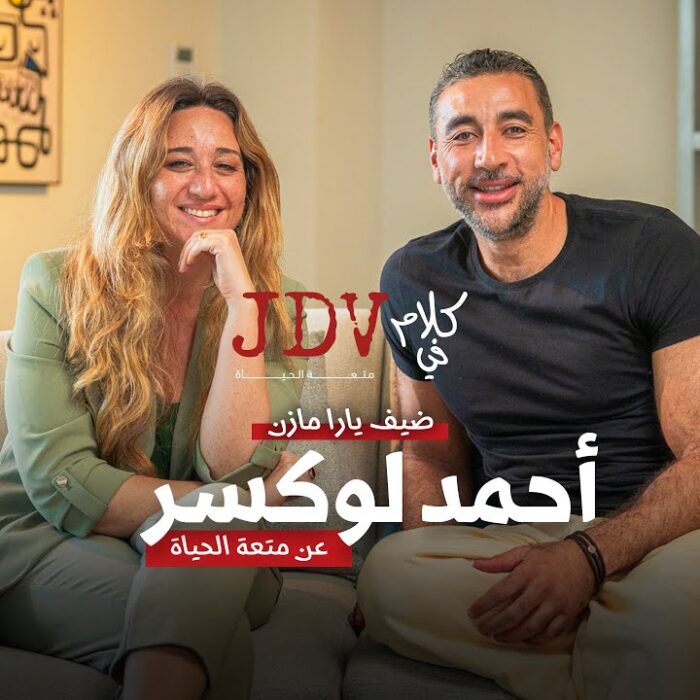 Relaxed couple sitting on couch in modern living room for JDV talk show about life, happiness, and personal stories, promoting engaging conversations in a cozy home environment.