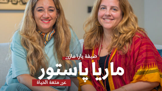 "Two women smiling happily, sitting together in a modern, well-lit interior, promoting Maria Baytor's life coaching for a meaningful life, with the JDV logo in the background.".