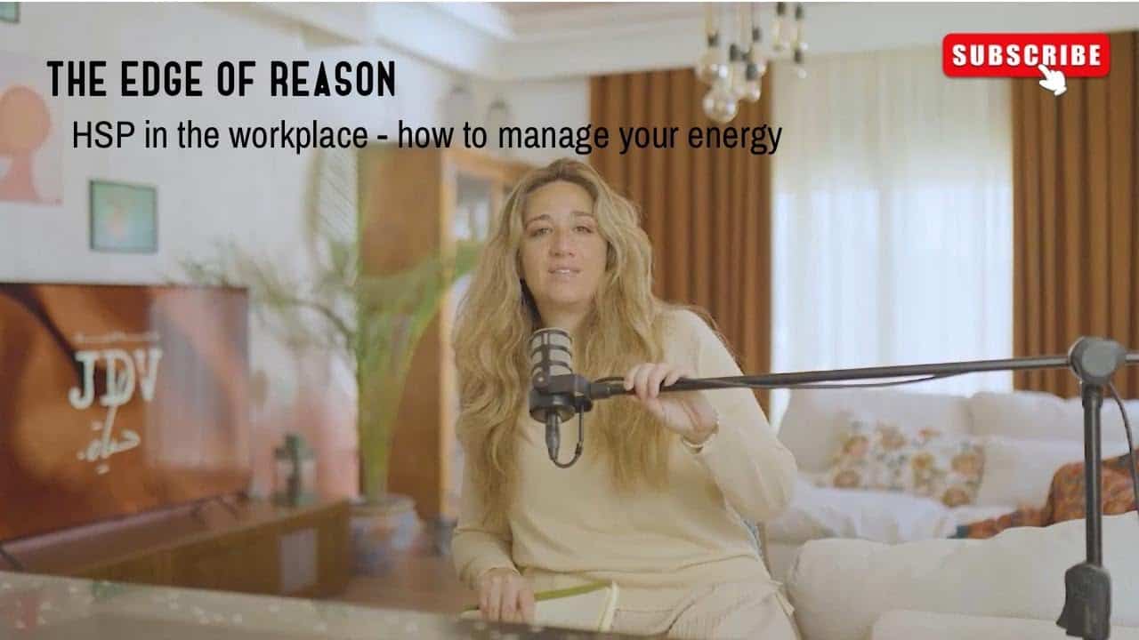 Natural woman speaking into a microphone during a podcast recording at home with a piano and cozy living room decor, promoting workplace health and safety.