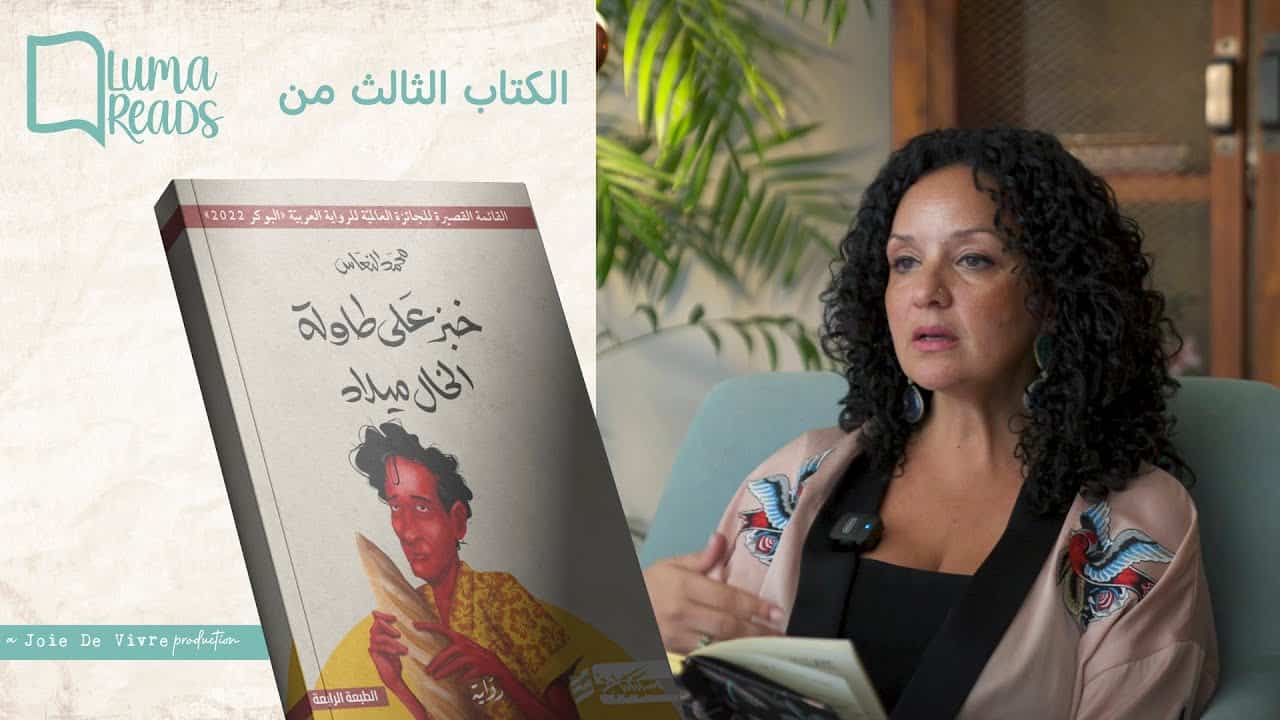 Thought-provoking image of a middle-aged woman with curly hair, sitting on a couch with a book in her hand, showcasing the importance of literature and personal development at JDV.
