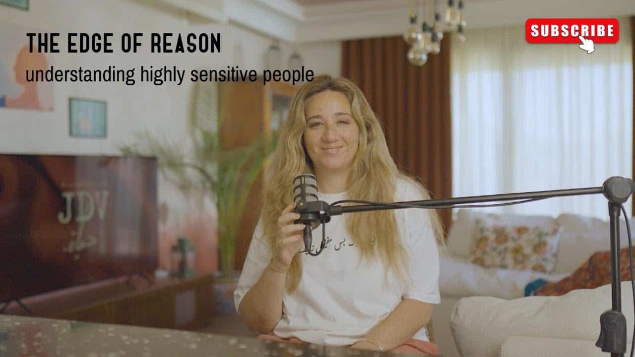 Relaxed woman with long blonde hair holding a microphone in a cozy living room, ready to record a podcast about understanding highly sensitive people, promoting awareness and empathy.